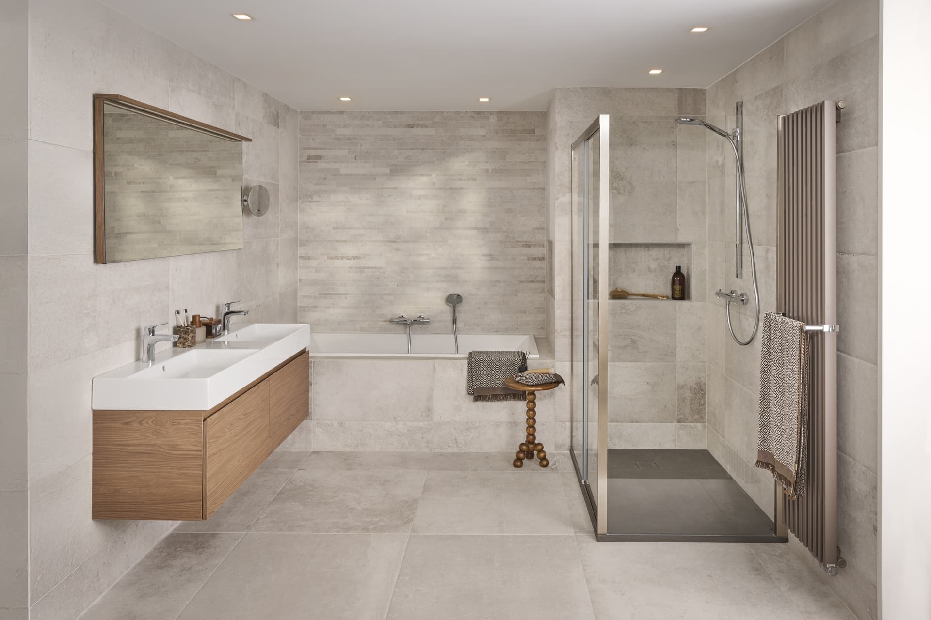 Beige badkamer met bad, donker hout meubel en glazen douchewand