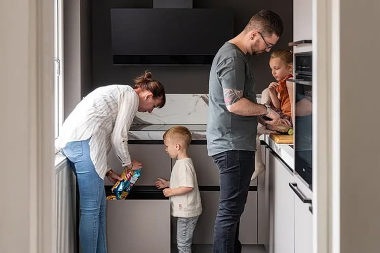 Beige hoekkeuken waar een gezin van 4 samen eten aan het klaarmaken is